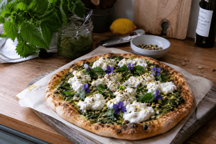 Brandnetel Pesto Pizza met burrata, citroenrasp, pistache en eetbare bloemen