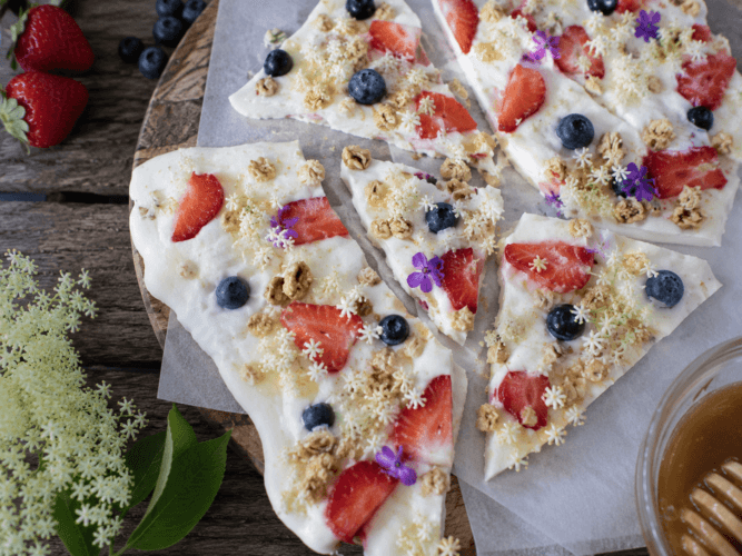 Vlierbloesem yoghurtbreekplaat met aardbei, blauwe bes en eetbare bloemen